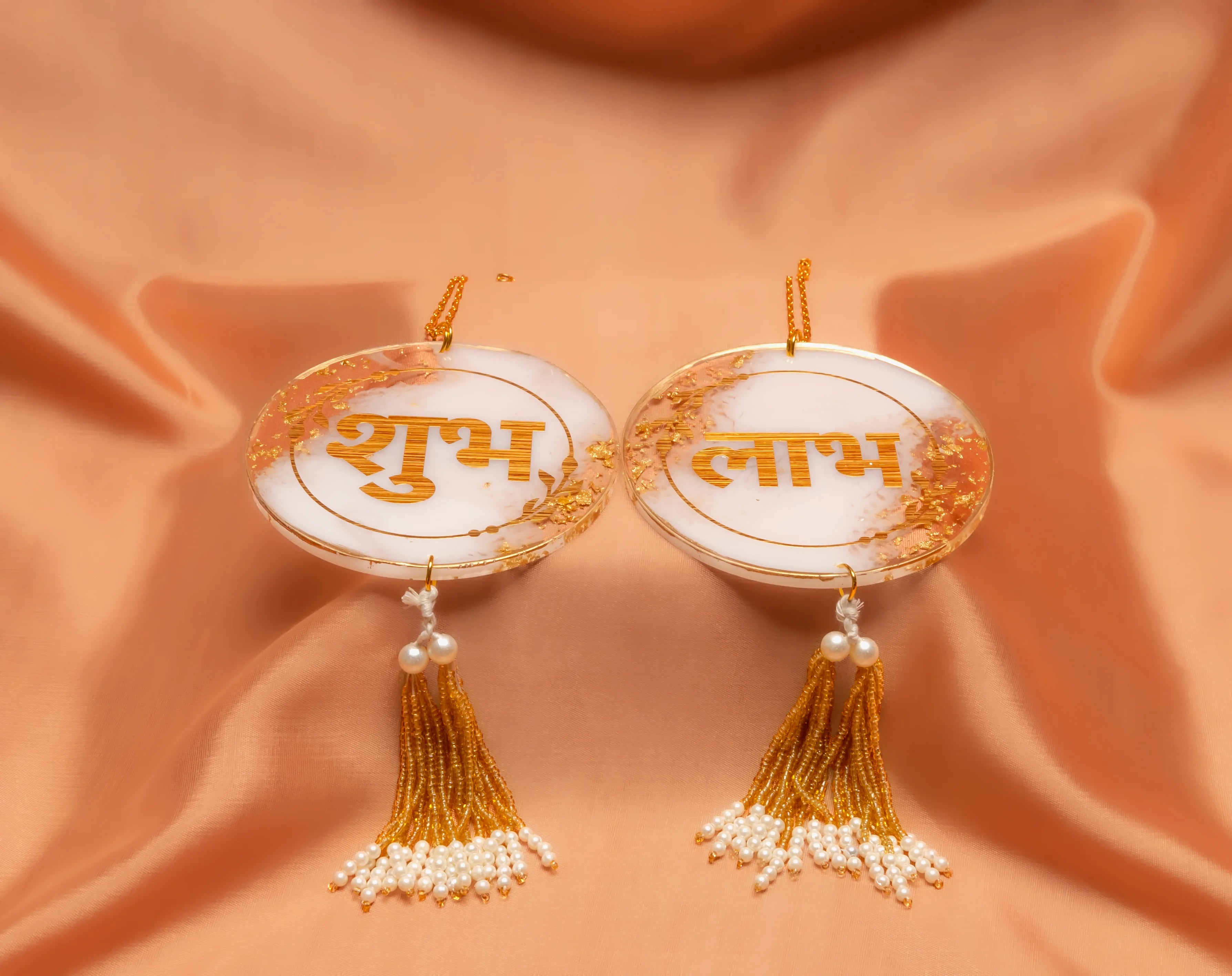 Decorative items with gold text and tassels on a peach fabric background