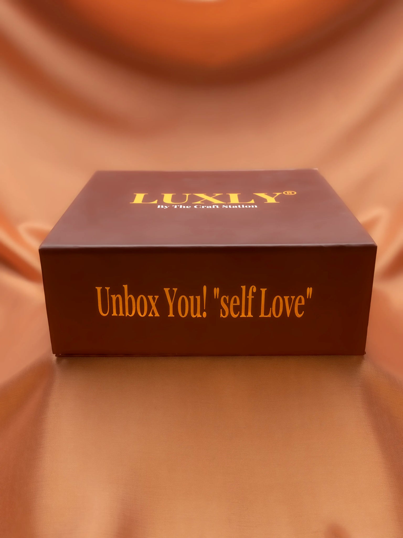 Brown box with 'Luxly' branding and text on a matching fabric background